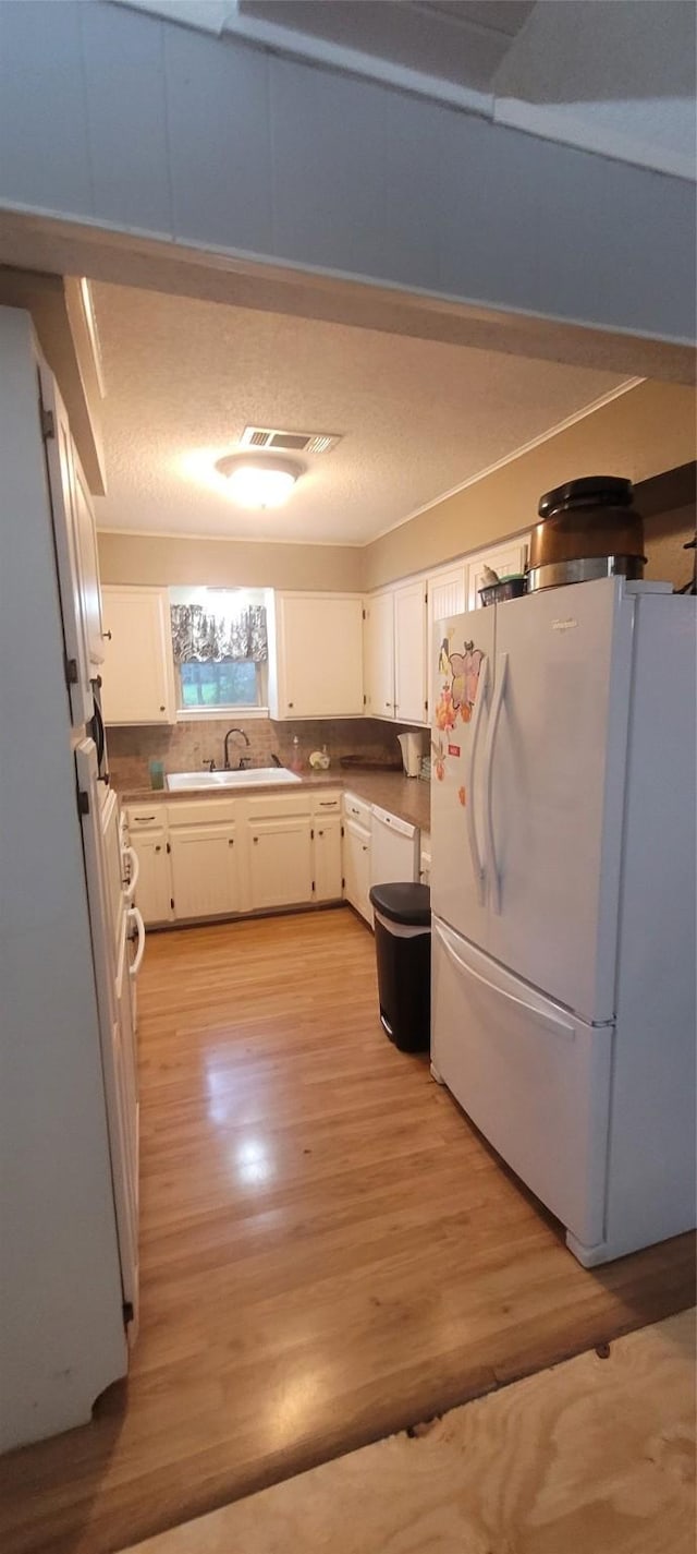 20 Connor Ln, Huntsville, TX 77320 - kitchen featuring white appliances, light wood-style floors, white cabinets, and light countertops