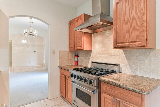1628 Vauthier St, La Marque, TX 77568 - kitchen with wall chimney range hood, stainless steel stove, arched walkways, light tile patterned flooring, and light colored carpet