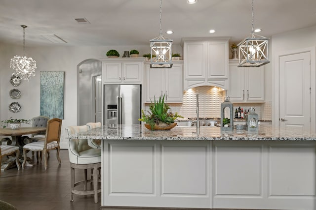 43 W Sawyer Ridge Dr, Spring, TX 77389 - kitchen featuring high end fridge, white cabinets, arched walkways, tasteful backsplash, and ventilation hood