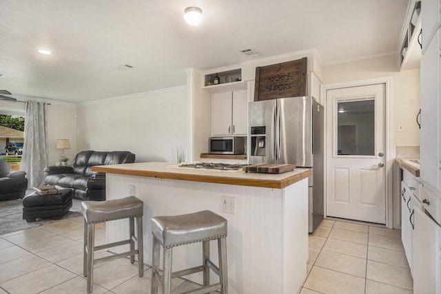 201 E 5th St, Deer Park, TX 77536 - kitchen with appliances with stainless steel finishes, butcher block counters, light tile patterned floors, a center island, and a breakfast bar area