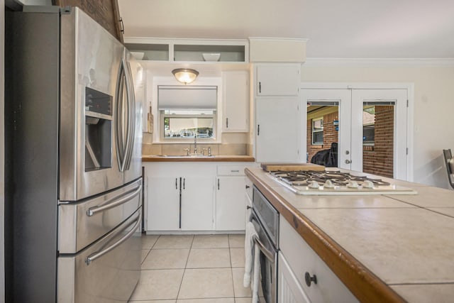 201 E 5th St, Deer Park, TX 77536 - kitchen featuring stainless steel appliances, white cabinets, french doors, light tile patterned floors, and crown molding