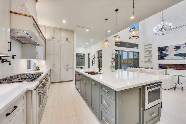 7106 Dearborn St, Houston, TX 77055 - kitchen with gray cabinetry, stainless steel appliances, light wood-style floors, a chandelier, and exhaust hood