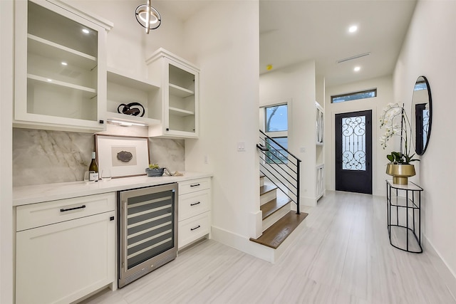 7106 Dearborn St, Houston, TX 77055 - indoor dry bar featuring wine cooler, stairs, backsplash, light wood-style flooring, and recessed lighting