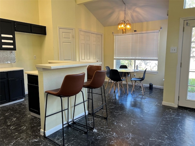 18534 Trail Bend Ln, Houston, TX 77084 - kitchen featuring dark cabinets, a chandelier, a kitchen bar, light countertops, and plenty of natural light