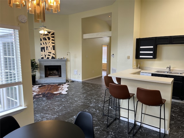 18534 Trail Bend Ln, Houston, TX 77084 - kitchen with dark cabinetry, healthy amount of natural light, a breakfast bar area, a brick fireplace, and a towering ceiling