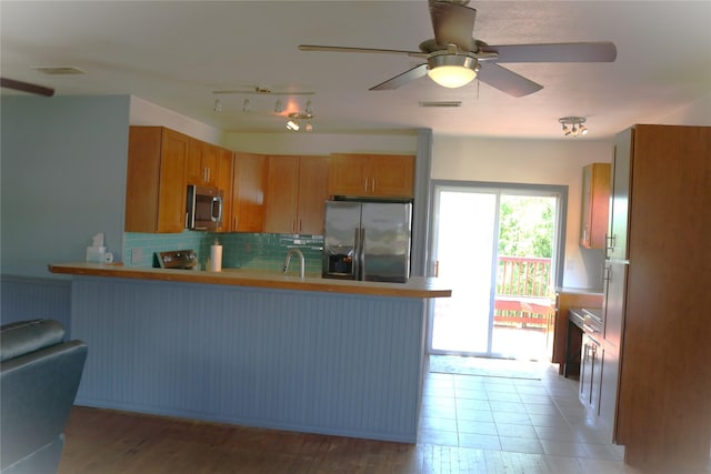 16542 John Silver Rd, Jamaica Beach, TX 77554 - kitchen with appliances with stainless steel finishes, a peninsula, tasteful backsplash, a ceiling fan, and light countertops