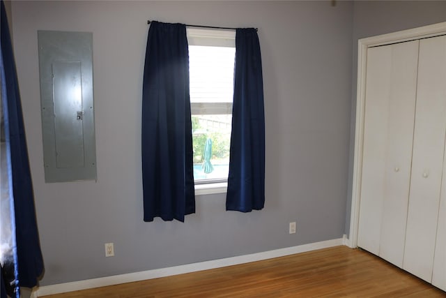 16542 John Silver Rd, Jamaica Beach, TX 77554 - unfurnished bedroom featuring electric panel, multiple windows, wood finished floors, and a closet