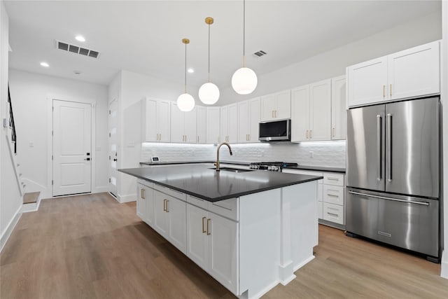 412 E 34th St, Houston, TX 77018 - kitchen with stainless steel appliances, dark countertops, tasteful backsplash, light wood-type flooring, and white cabinetry