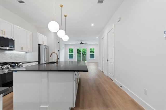 412 E 34th St, Houston, TX 77018 - kitchen with appliances with stainless steel finishes, dark countertops, white cabinets, light wood finished floors, and backsplash