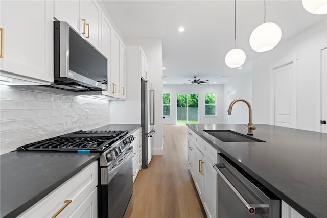 412 E 34th St, Houston, TX 77018 - kitchen with stainless steel appliances, light wood-style floors, white cabinets, tasteful backsplash, and hanging light fixtures