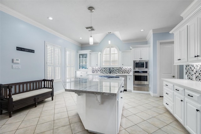 983 W 42nd St, Houston, TX 77018 - kitchen featuring stainless steel appliances, tasteful backsplash, white cabinets, light tile patterned floors, and ornamental molding