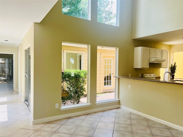 11530 Bellerive Dr, Houston, TX 77072 - kitchen with under cabinet range hood, light tile patterned floors, plenty of natural light, and a towering ceiling
