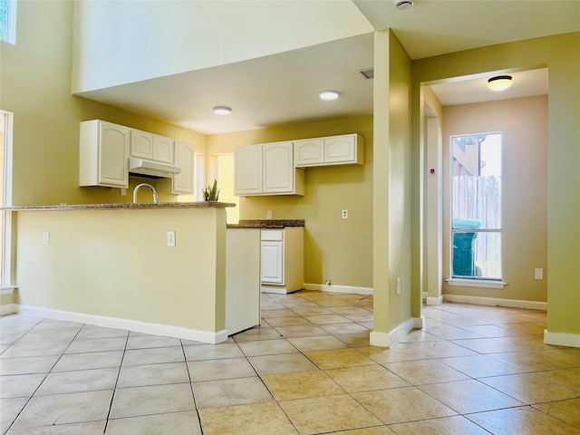 11530 Bellerive Dr, Houston, TX 77072 - kitchen featuring under cabinet range hood, white cabinets, light tile patterned floors, and a peninsula