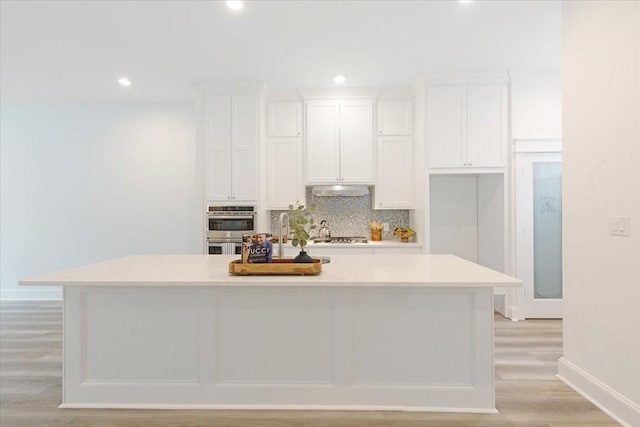 6723 Saint Augustine St, Houston, TX 77021 - kitchen featuring white cabinetry, double oven, light wood-type flooring, backsplash, and recessed lighting