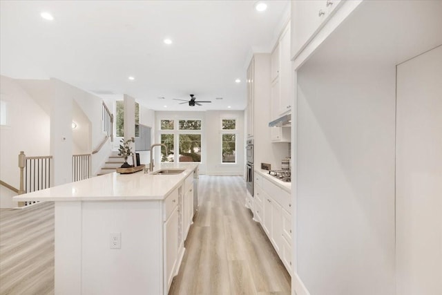 6723 Saint Augustine St, Houston, TX 77021 - kitchen with light wood-style flooring, a ceiling fan, an island with sink, white cabinetry, and light countertops