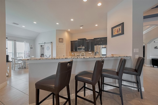 4227 Lodge Ranch Ct, Fulshear, TX 77441 - kitchen featuring stainless steel appliances, a breakfast bar area, light stone countertops, light tile patterned floors, and vaulted ceiling