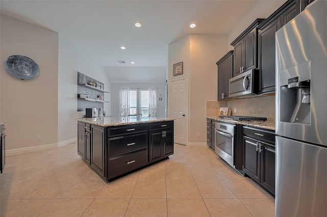 4227 Lodge Ranch Ct, Fulshear, TX 77441 - kitchen featuring appliances with stainless steel finishes, dark cabinetry, light tile patterned floors, a center island, and recessed lighting
