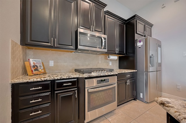 4227 Lodge Ranch Ct, Fulshear, TX 77441 - kitchen featuring appliances with stainless steel finishes, decorative backsplash, light tile patterned floors, light stone countertops, and dark cabinets