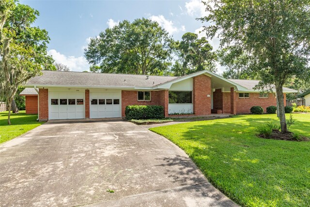 122 Blossom St, Lake Jackson, TX 77566 - ranch-style house featuring a garage, concrete driveway, brick siding, and a front lawn