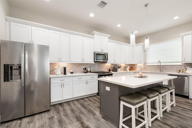 3342 Pinemont Dr, Houston, TX 77018 - kitchen featuring stainless steel appliances, white cabinets, a kitchen bar, and recessed lighting
