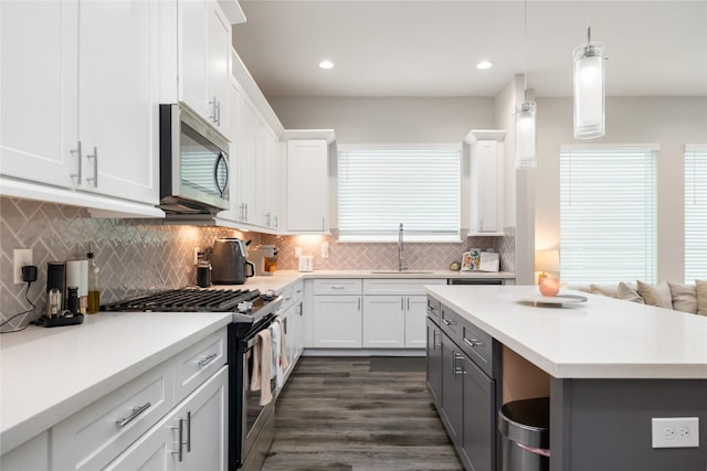 3342 Pinemont Dr, Houston, TX 77018 - kitchen with stainless steel appliances, light countertops, white cabinets, backsplash, and decorative light fixtures