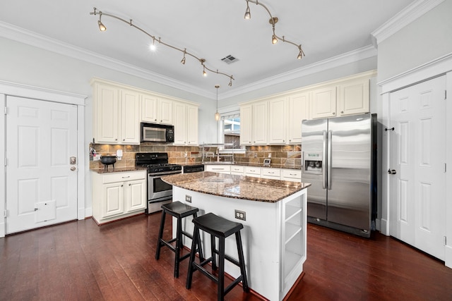 2111 Beall St, Houston, TX 77008 - kitchen with stainless steel appliances, cream cabinets, a center island, dark stone counters, and dark wood-type flooring