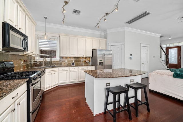 2111 Beall St, Houston, TX 77008 - kitchen featuring stainless steel appliances, crown molding, open floor plan, a kitchen breakfast bar, and tasteful backsplash