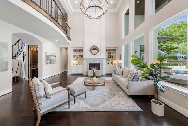 8550 Tombron Grove Rd, Magnolia, TX 77354 - living area with a high ceiling, wood finished floors, a lit fireplace, a chandelier, and built in features