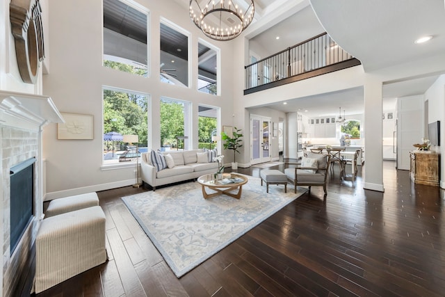 8550 Tombron Grove Rd, Magnolia, TX 77354 - living area featuring a tiled fireplace, a chandelier, a towering ceiling, and hardwood / wood-style floors
