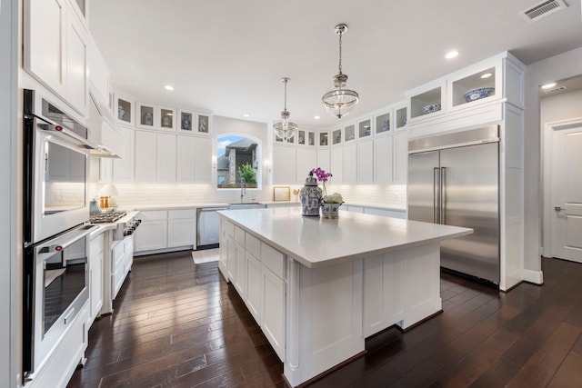 8550 Tombron Grove Rd, Magnolia, TX 77354 - kitchen with stainless steel appliances, a kitchen island, light countertops, white cabinets, and backsplash