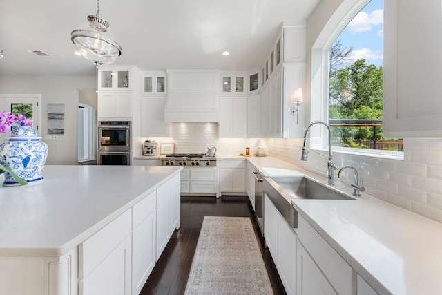 8550 Tombron Grove Rd, Magnolia, TX 77354 - kitchen with appliances with stainless steel finishes, custom exhaust hood, tasteful backsplash, white cabinets, and light countertops
