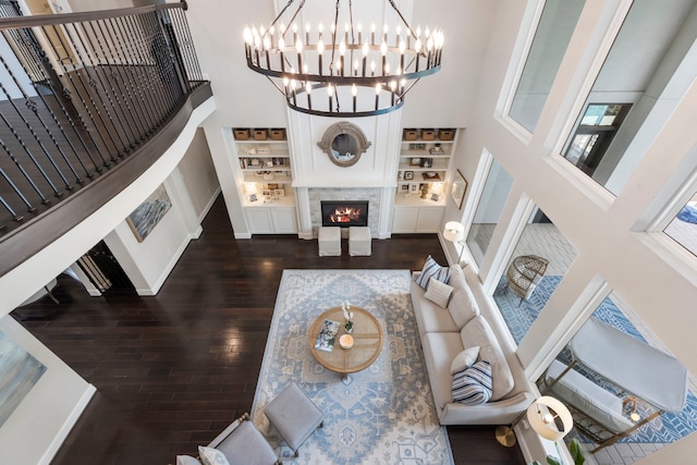 8550 Tombron Grove Rd, Magnolia, TX 77354 - living area with a high ceiling, dark wood-style flooring, built in shelves, a chandelier, and a fireplace