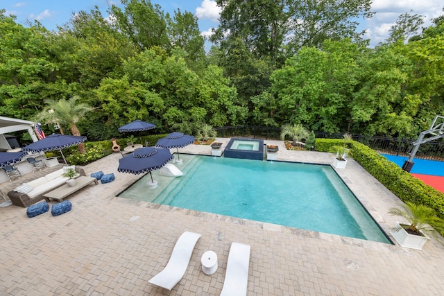 8550 Tombron Grove Rd, Magnolia, TX 77354 - view of swimming pool featuring a patio, view of wooded area, and a pool with connected hot tub