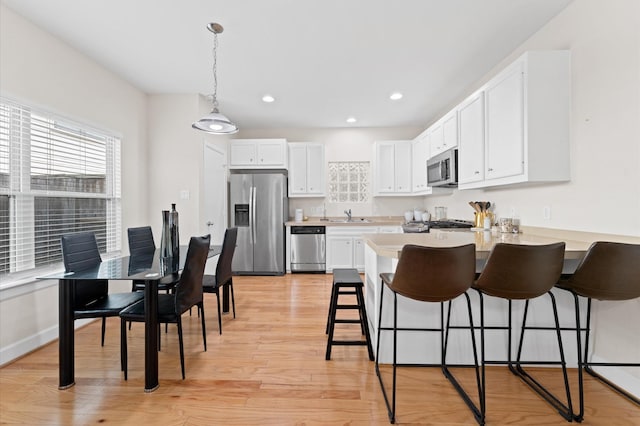 3736 Main Poplar Dr, Houston, TX 77025 - kitchen with stainless steel appliances, a peninsula, a kitchen breakfast bar, white cabinets, and recessed lighting