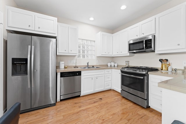 3736 Main Poplar Dr, Houston, TX 77025 - kitchen featuring stainless steel appliances, white cabinets, recessed lighting, and light wood-type flooring