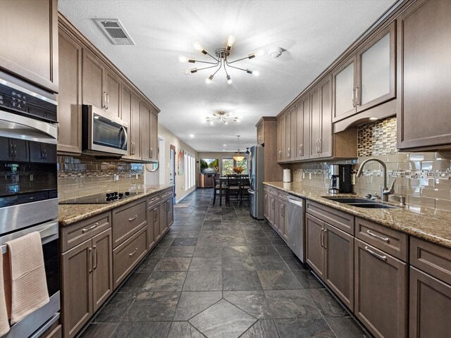 4710 Mckeever Ln, Missouri City, TX 77459 - kitchen featuring a chandelier, stainless steel appliances, dark stone finish floors, tasteful backsplash, and light stone countertops