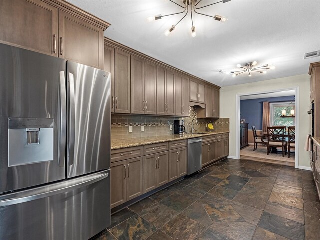 4710 Mckeever Ln, Missouri City, TX 77459 - kitchen featuring stainless steel appliances, a chandelier, backsplash, stone tile flooring, and light stone counters