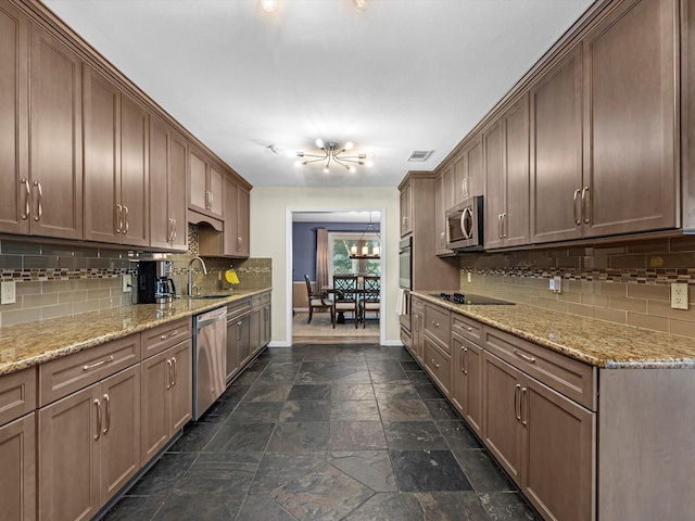4710 Mckeever Ln, Missouri City, TX 77459 - kitchen with stainless steel appliances, stone tile flooring, backsplash, a chandelier, and light stone counters