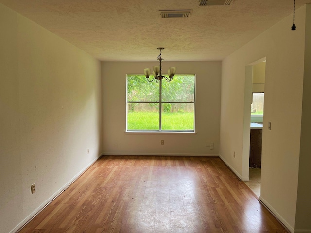 12138 Flaxen Dr, Houston, TX 77065 - unfurnished room with a chandelier, wood finished floors, plenty of natural light, and a textured ceiling
