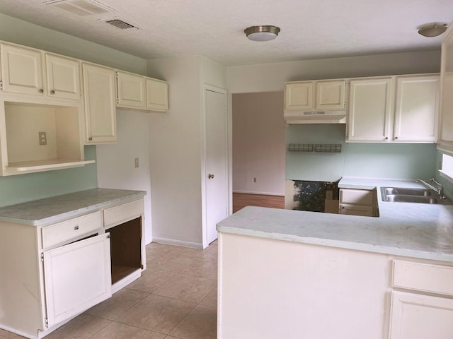 12138 Flaxen Dr, Houston, TX 77065 - kitchen with under cabinet range hood, a peninsula, light tile patterned floors, and white cabinets