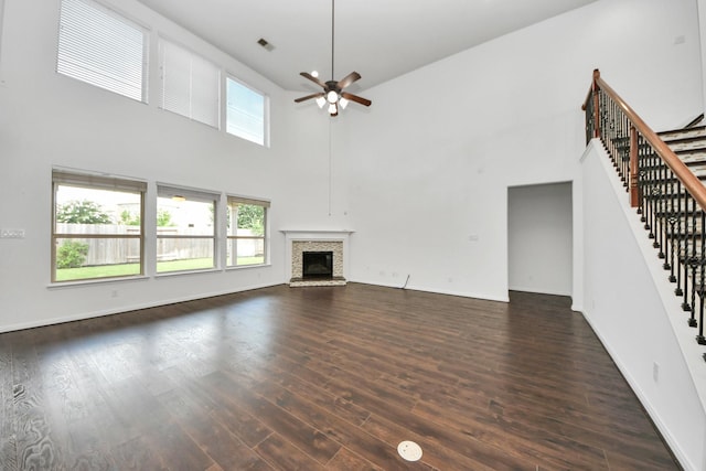 4330 Lasker Brook Ct, Katy, TX 77494 - unfurnished living room featuring a towering ceiling, a ceiling fan, stairs, dark wood-type flooring, and a fireplace with raised hearth