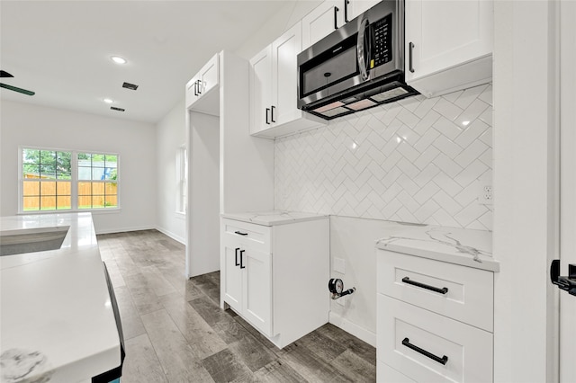 7922 Sealey St, Houston, TX 77088 - kitchen with stainless steel microwave, tasteful backsplash, recessed lighting, light stone countertops, and white cabinetry