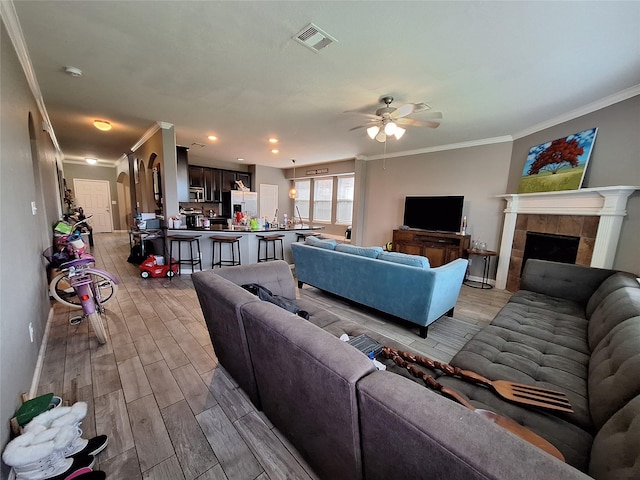 20331 Weeping Pine Way, Richmond, TX 77407 - living room with crown molding, light wood finished floors, ceiling fan, and a tiled fireplace