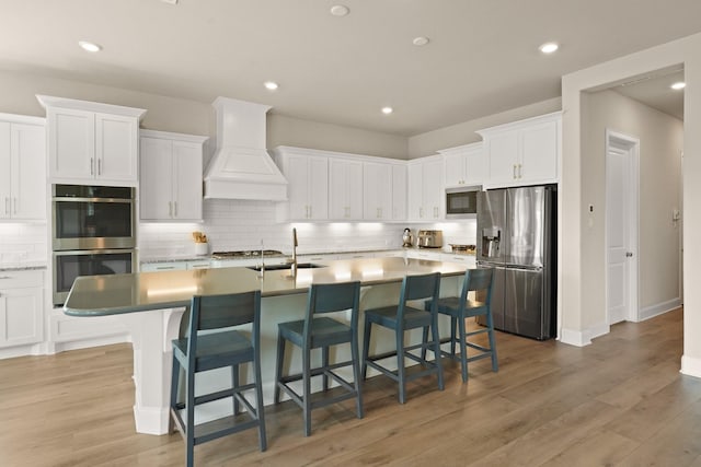 6919 Shoreline View Dr, Katy, TX 77493 - kitchen featuring stainless steel appliances, custom range hood, decorative backsplash, white cabinets, and recessed lighting