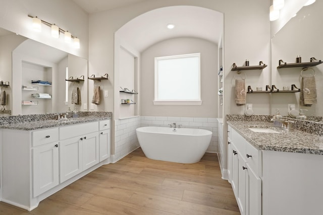 6919 Shoreline View Dr, Katy, TX 77493 - full bath featuring wood finished floors, two vanities, wainscoting, a soaking tub, and tile walls