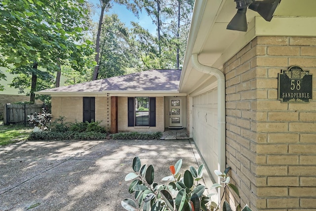58 Sandpebble Dr, Spring, TX 77381 - view of exterior entry featuring brick siding, a shingled roof, and an attached garage