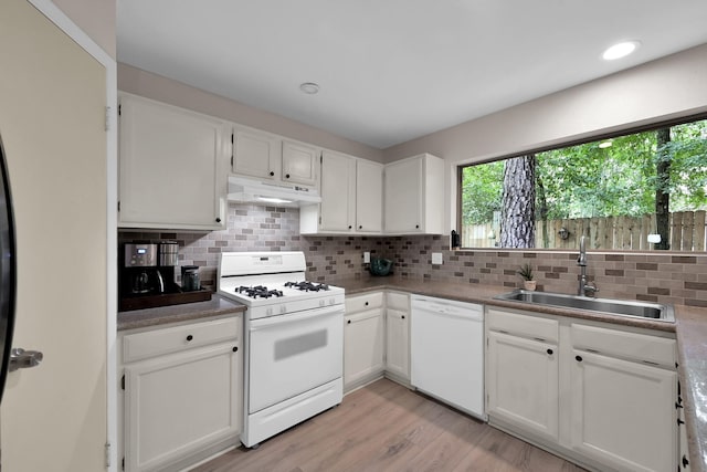 58 Sandpebble Dr, Spring, TX 77381 - kitchen with white appliances, under cabinet range hood, tasteful backsplash, light wood finished floors, and white cabinetry