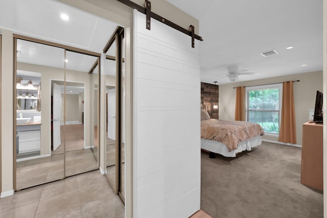 58 Sandpebble Dr, Spring, TX 77381 - bedroom with a barn door, recessed lighting, light tile patterned floors, and light colored carpet