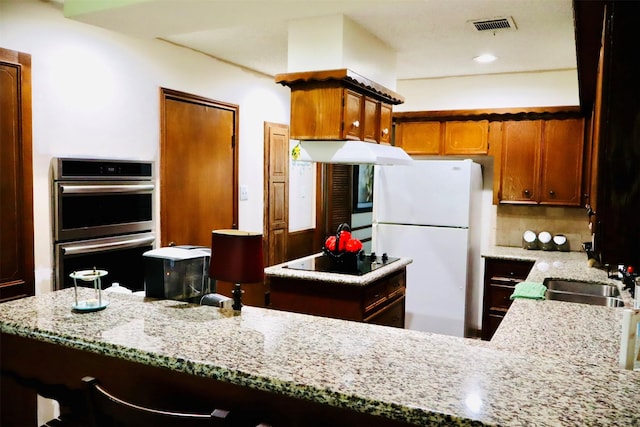 1108 Easy St, Rosenberg, TX 77471 - kitchen featuring freestanding refrigerator, double oven, black electric stovetop, light stone countertops, and backsplash