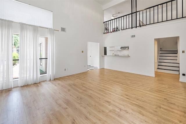 8033 Oakwood Forest Dr, Houston, TX 77040 - unfurnished living room with a towering ceiling, stairs, wood finished floors, and ceiling fan